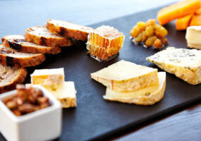 Fancy cheese plate with blue cheese, cheddar, goat cheese, bread, honey and pistachios at a luxury restaurant.  Horizontal shot. High angle view.